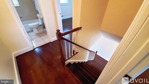 A staircase with a wooden handrail and a white wall.