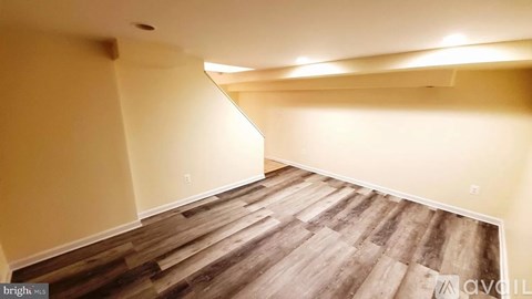 A room with wooden flooring and a corner that is empty.