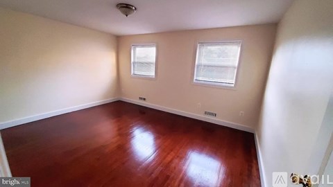 A room with wooden floors and two windows.