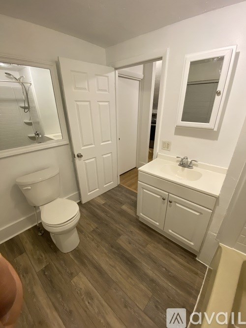 A bathroom with a toilet, sink, and mirror.