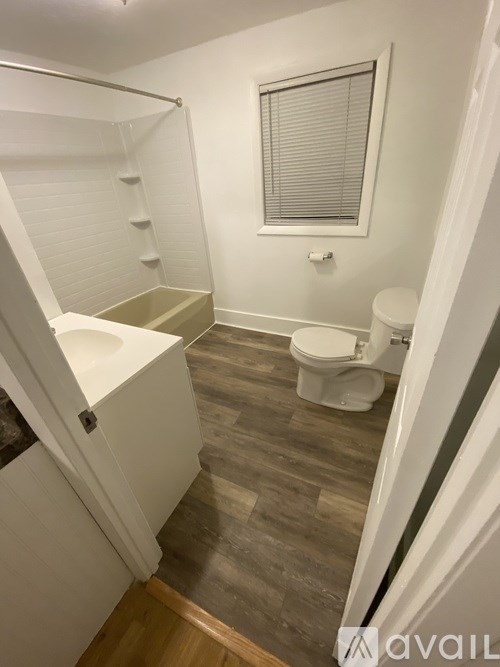 A bathroom with a toilet, sink, and a window.