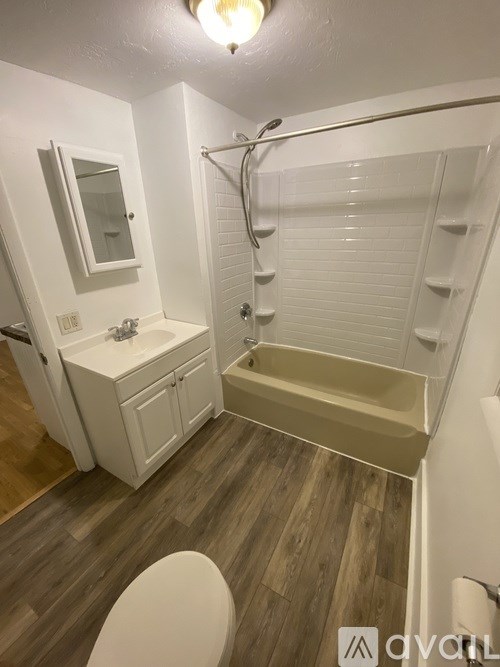A white bathroom with a wooden floor and a white toilet.