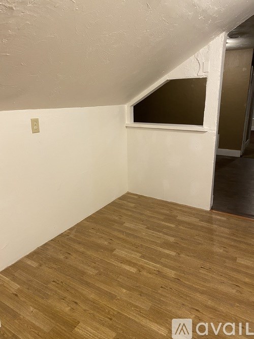 A room with wooden flooring and a window.