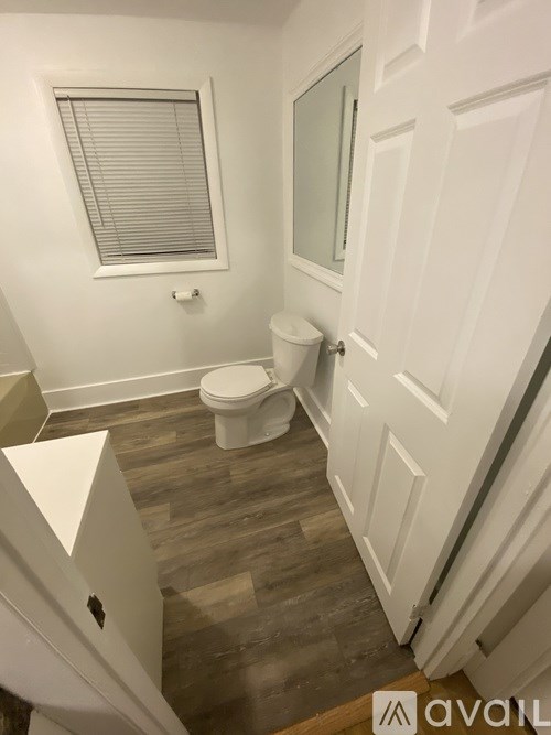 A bathroom with a toilet, sink, and wooden floors.