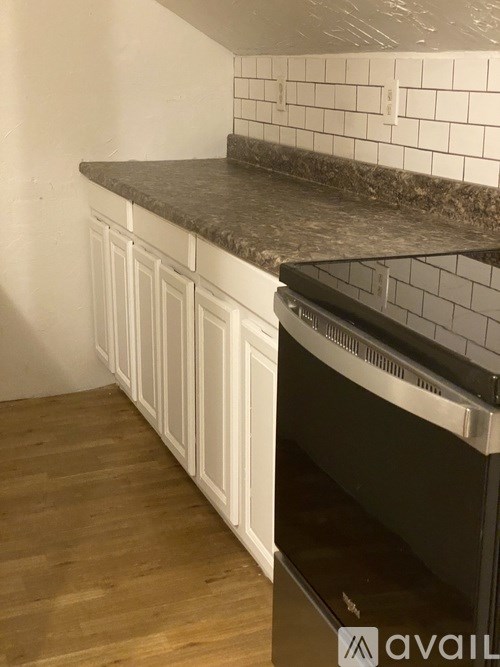 A kitchen with a black oven and white cabinets.
