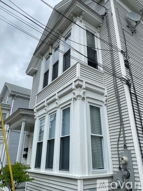 A grey house with white trim and a window with a white frame.