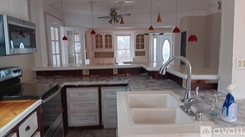 A kitchen with a sink, a stove, and a ceiling fan.