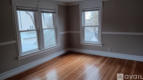 A room with wooden floors and two windows.