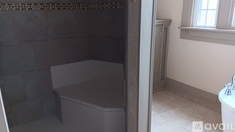 A white bathtub sits in a bathroom with grey tiled walls.