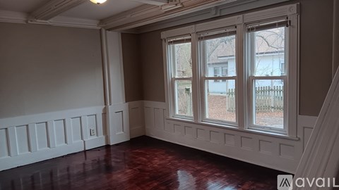 A room with a large window and wooden flooring.