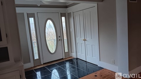 A room with a white door and a window with a stained glass design.