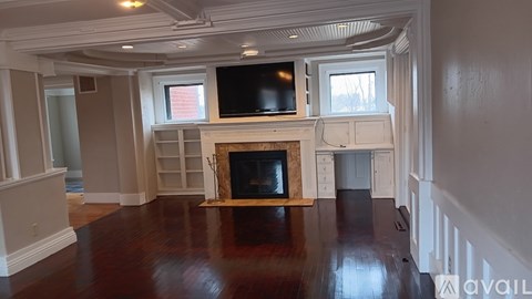 A living room with a fireplace and a television on the wall.
