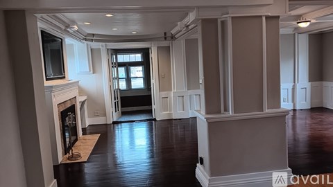 A spacious room with wood flooring and a fireplace.