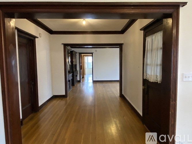 A long hallway with wooden floors and white walls.