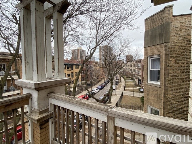 A balcony with a view of a street lined with parked cars and buildings.