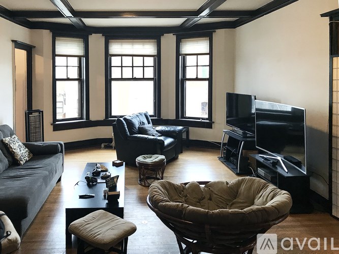 A living room with a grey couch, a black television, and a wooden floor.