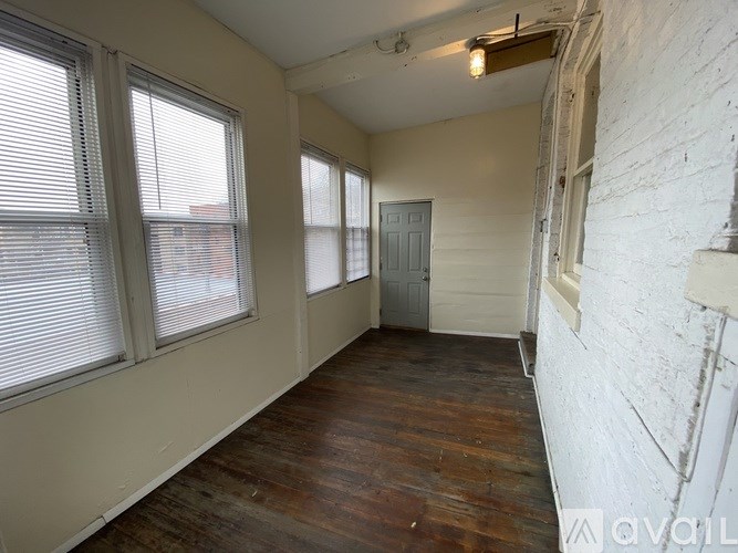 A room with wooden floors and white walls, with a door in the middle of the room.