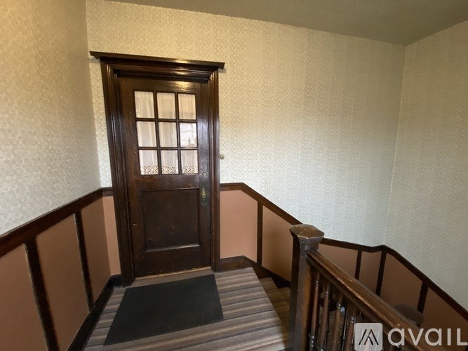 A wooden door with a glass window is at the end of a staircase.
