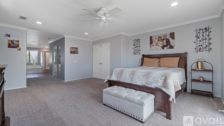 A bedroom with a bed, bench, and pictures on the wall.