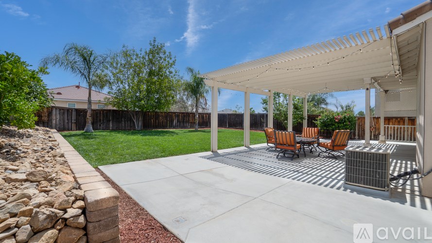 A patio with a white pergola and four chairs.
