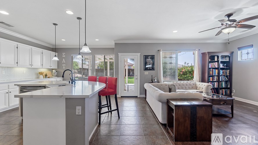 A modern kitchen with white cabinets and a red bar stool.