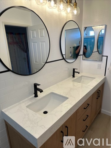 A bathroom with a marble countertop and two round mirrors.