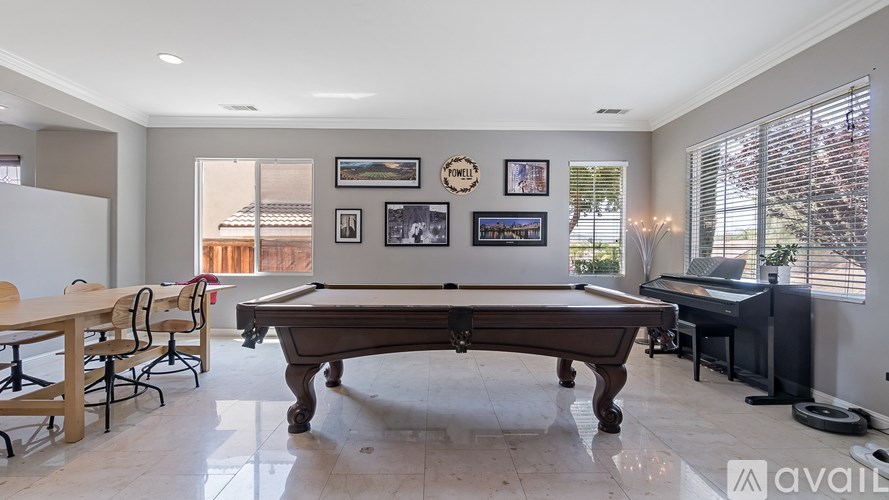 A pool table is in the middle of a room with a piano and a dining table.