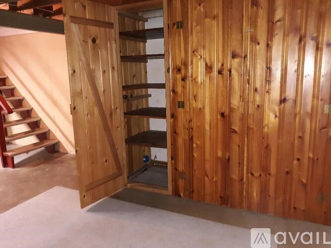 A wooden wall with a door open to a staircase.