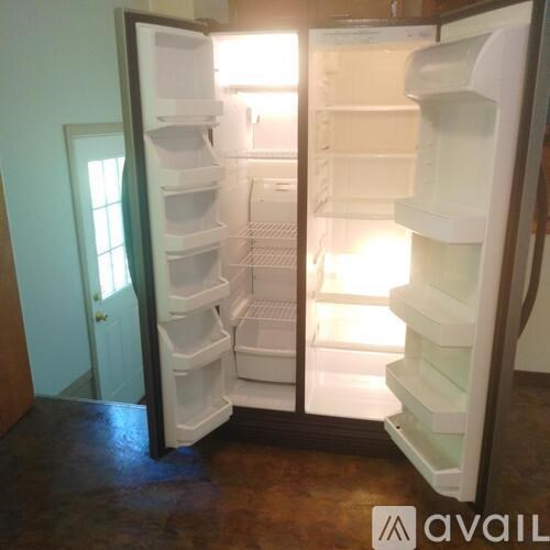 A white refrigerator with its door open in a room.