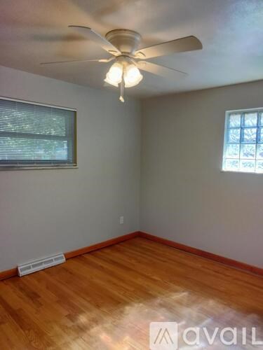 A room with a ceiling fan and wooden flooring.