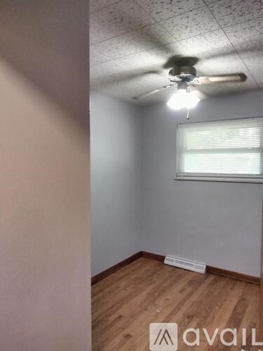A room with a ceiling fan and a window with blinds.