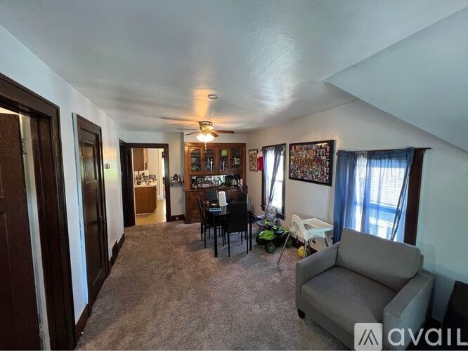 A living room with a grey couch and a dining table with chairs.