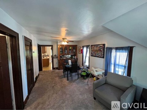 A living room with a grey couch and a dining table with chairs.