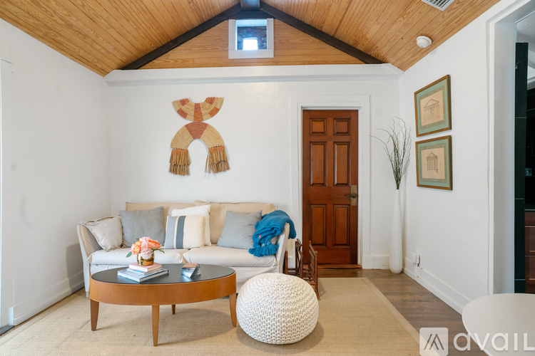 A living room with a white couch, a wooden coffee table, and a white ottoman.