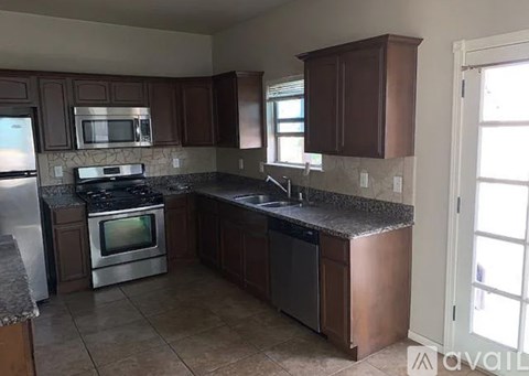A kitchen with brown cabinets and a granite countertop.