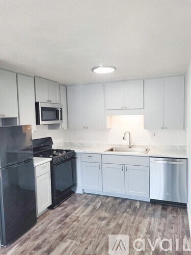 A kitchen with black appliances and white cabinets.