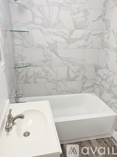 A white sink with a silver faucet is in front of a marble wall.