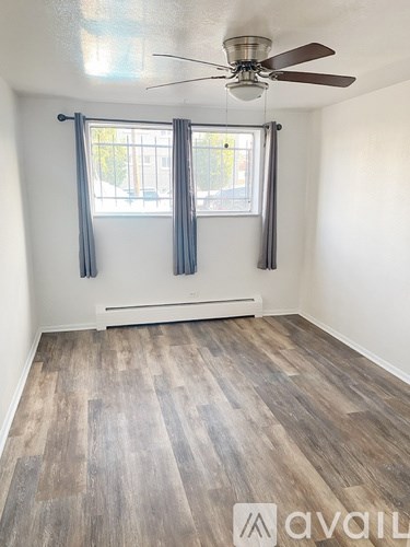 A room with a ceiling fan and a window with curtains.