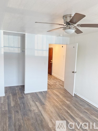 A room with a ceiling fan and wooden flooring.