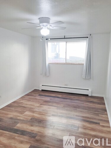 A room with a ceiling fan and a window with curtains.