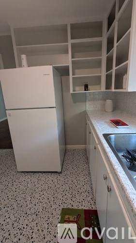 A kitchen with a white fridge and a tiled floor.