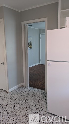 A white fridge in a kitchen with a white door and a white cabinet.