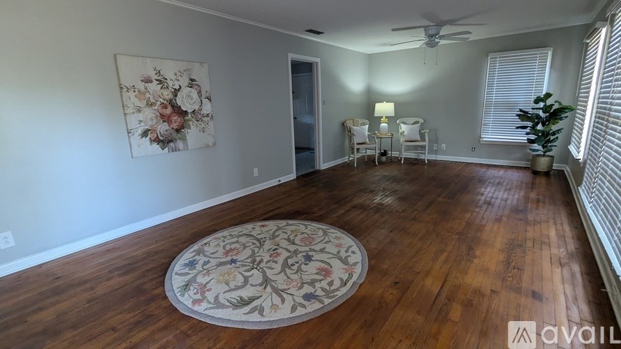 A room with a floral rug on the floor and a painting on the wall.