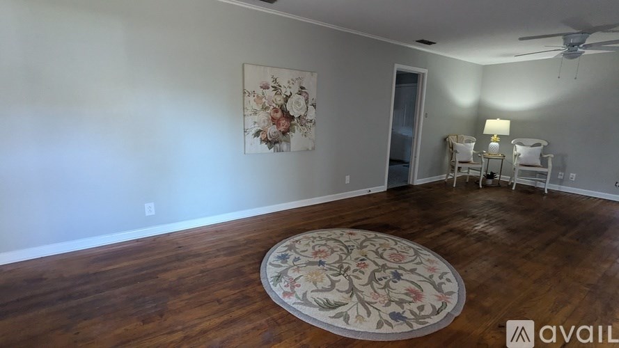 A room with a floral rug on the floor and a painting on the wall.