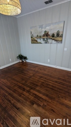 A room with wooden flooring and a painting on the wall.