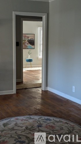 A hallway with a rug on the floor and a doorway leading to another room.
