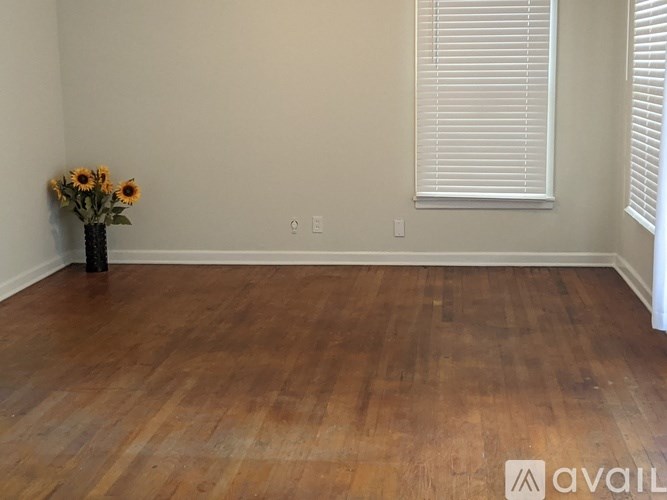 A room with wooden floors and a vase of sunflowers.