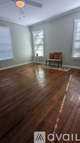 A room with wooden flooring and a bench under a window.