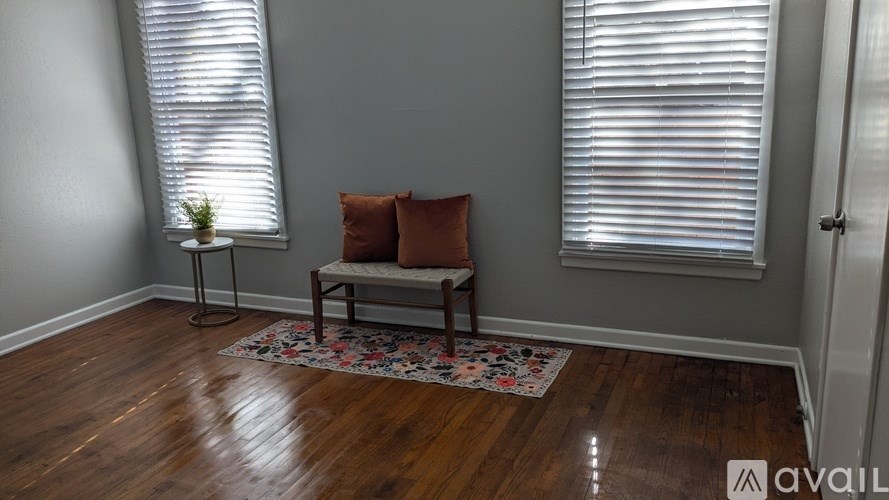 A room with a bench and a plant in front of a window.