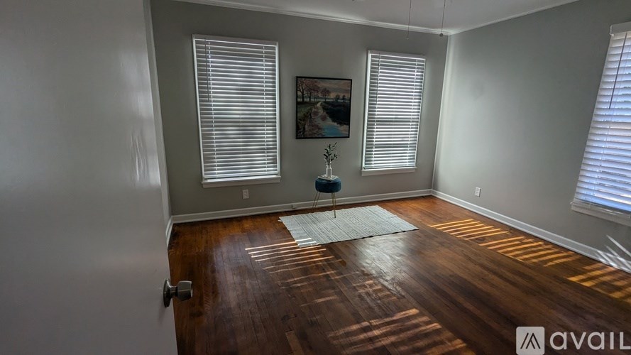 A room with wooden floors and a rug in the middle.